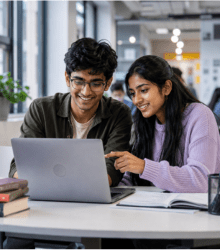 Two students collaborating on a laptop in a modern study environment.